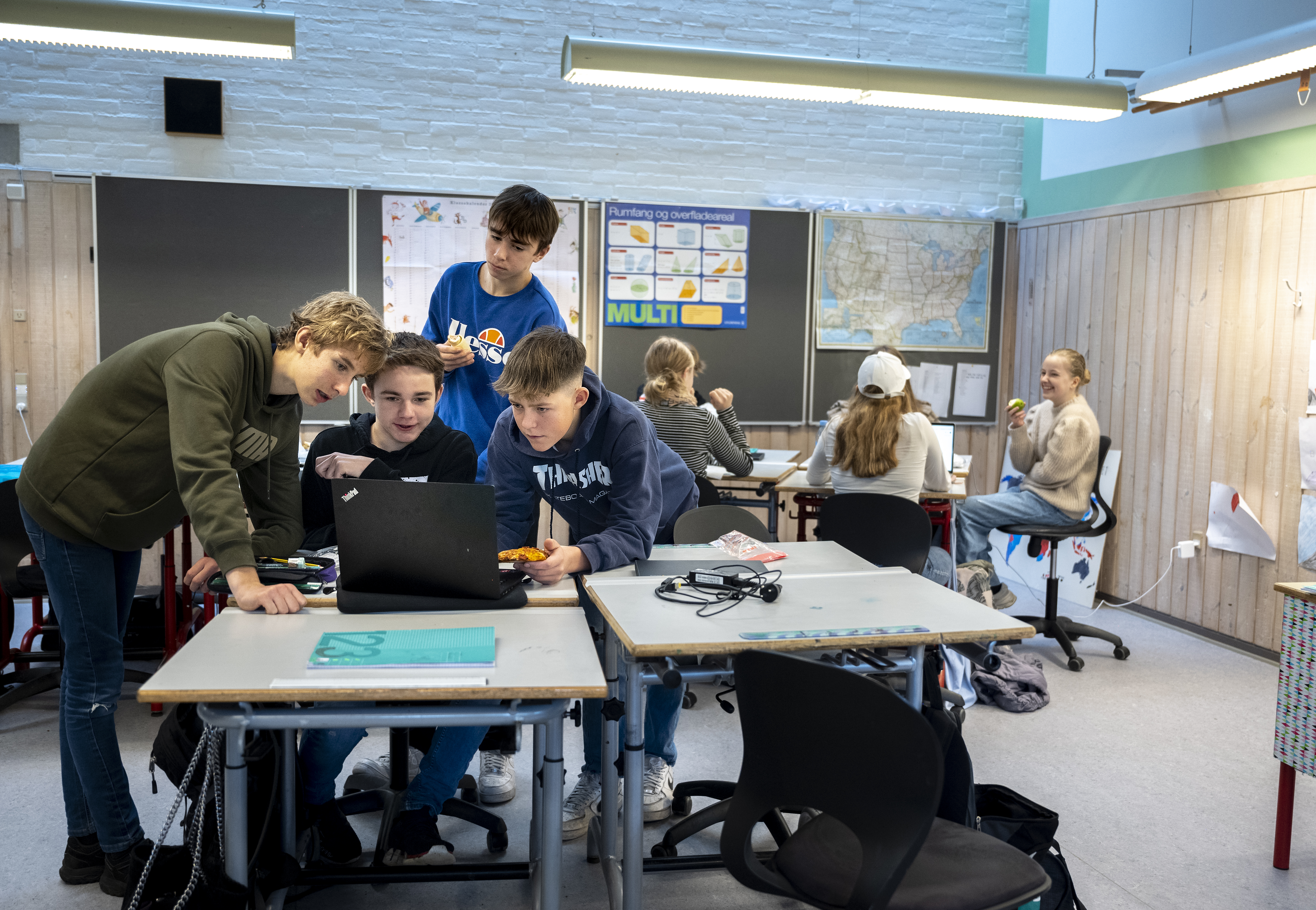 Fire drenge fra Rantzausminde Skole står bøjet over en bærbar computer i deres klasselokale
