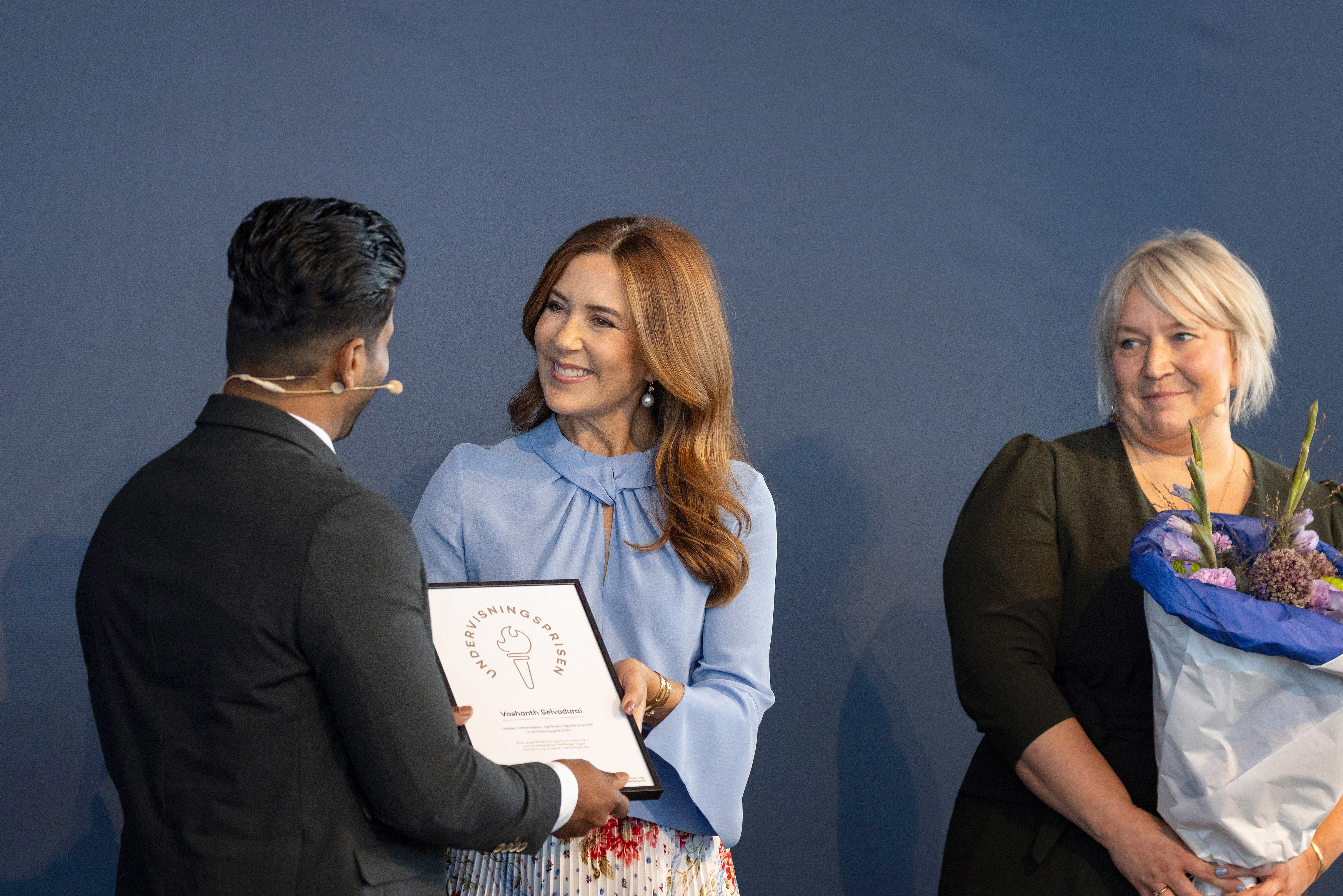 Vashanth Selvadurai, vinder af Undervisningsprisen 2024 får overrakt diplom og blomster af H. M. Dronningen og uddannelses- og forskningsminister Christina Egelund.